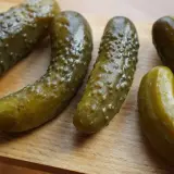 Kilka ogórków kiszonych leżących na drewnianej desce.
